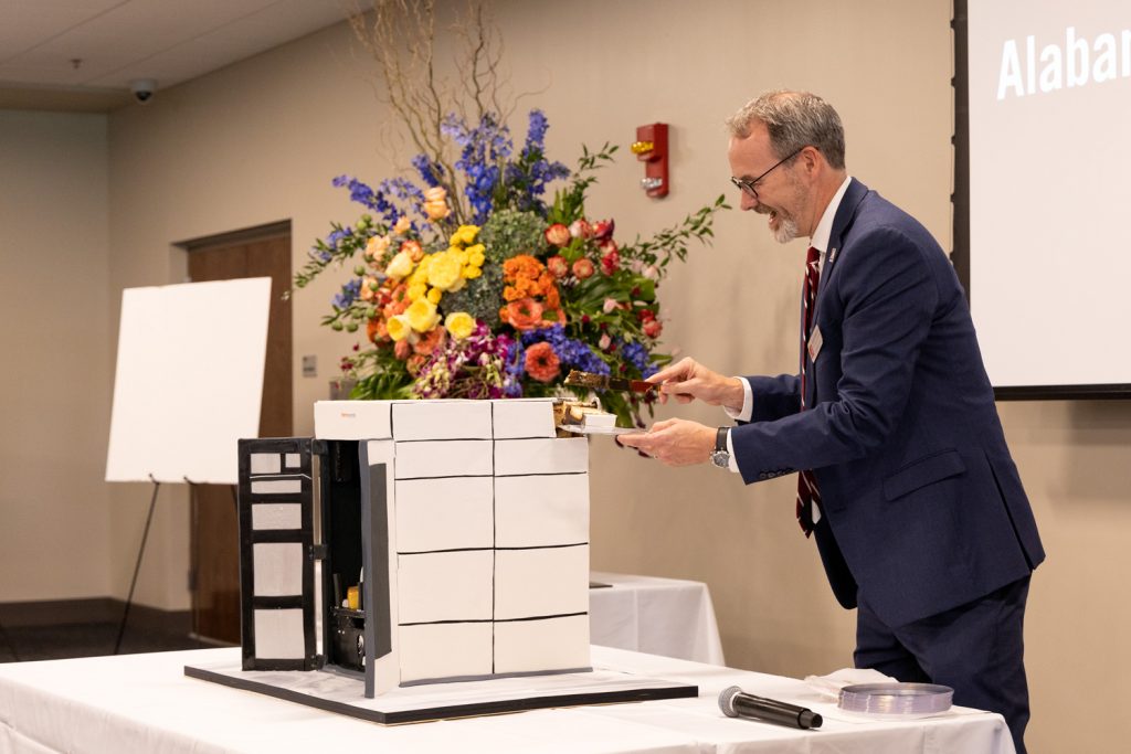 Dr. Greg Thompson cutting cake for open house attendees